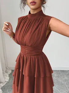 Dettaglio di un abito corto a balze senza maniche terracotta con un design in vita a punto smock