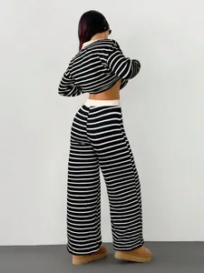 Vista posteriore di un set chic in maglia a righe bianche e nere con pantaloni larghi.