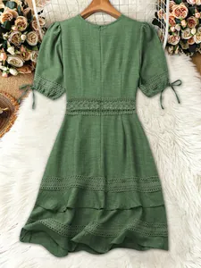 Dettaglio di un abito verde a maniche corte con inserti in pizzo e lacci alle maniche