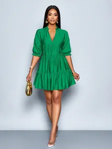 Detail view of a bright green tiered mini dress with V-neck and puff sleeves styling