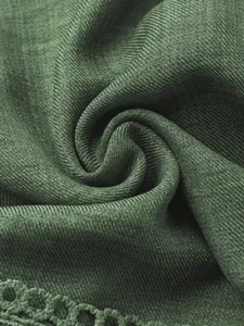 Primo piano della trama del tessuto verde scuro e dei dettagli in pizzo di questo abito