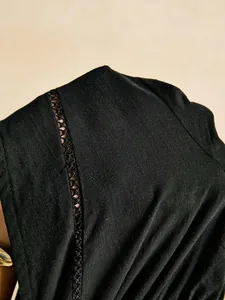 Close-up of black blouse showing intricate hollow-out lace and textured fabric detail