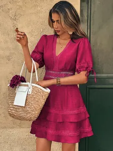Dettaglio di un abito magenta corto con scollo a V, pizzo e maniche a palloncino