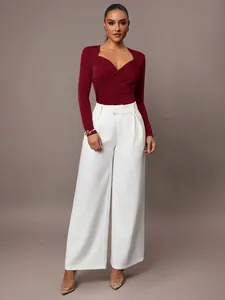 Elegante body bordeaux con scollo a V incrociato e pantaloni bianchi a gamba larga