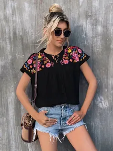 Detailed view of the vibrant embroidery and tassel necktie on the black boho blouse.