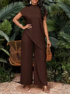Detalle del conjunto marrón con top de dobladillo irregular y pantalón ancho en escena tropical