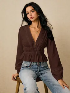 Detailed view of dark brown deep V-neck blouse with lace trim and tie-waist design.