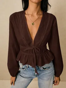 Detailed shot of a brown deep V-neck blouse featuring delicate lace trim and ruffle hem.