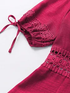 Dettaglio della manica di un abito bordeaux con pizzo elegante e laccetto regolabile