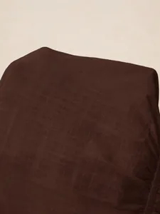 Detailed close-up showing the dark brown mesh fabric texture of the ruffled hem shirt.