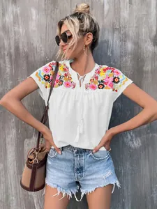 Bohemian white blouse featuring colorful shoulder embroidery and tassel tie-neck details