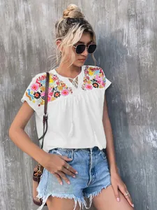Stylish white bohemian blouse featuring vibrant embroidery and tassel neck tie details