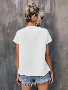 Back view of a minimalist white short sleeve summer shirt paired with denim shorts