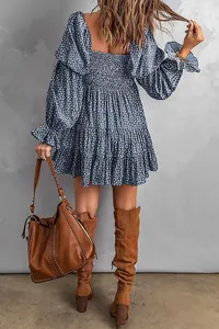 Rückansicht eines blauen floralen Off-Shoulder-Minikleides mit Stufenrock und Stiefeln.