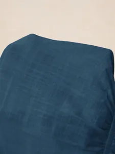 Close-up detail of the deep blue textured fabric of a V-neck blouse with stylish ruffles.