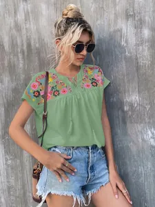 Detailed view of green summer blouse with colorful embroidery and tassel neck tie
