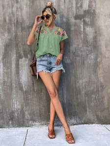 Light green blouse featuring intricate shoulder embroidery and tassel tie neckline detail