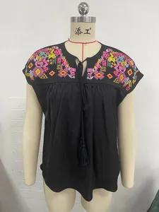 Close-up view of a black embroidered blouse featuring a tassel drawstring and colorful patterns