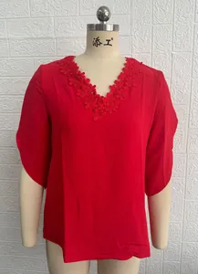 Close-up detail of a bright red V-neck blouse featuring delicate floral lace embroidery.