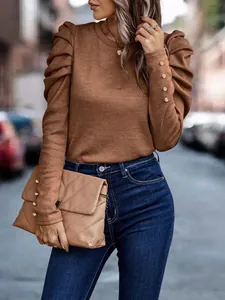 Detailed view of elegant puff shoulders and golden cuff buttons on a slim-fit brown knit sweater