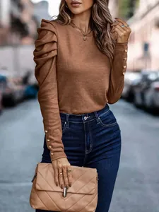 Detailed view of brown knit top featuring pleated puff sleeves and elegant button cuffs