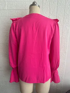Vista posteriore dell'elegante camicetta magenta con spalle a volant e polsini svasati