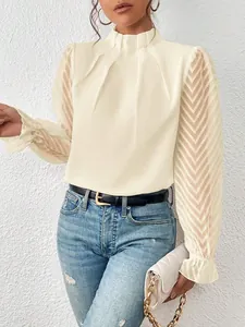 Λεπτομέρεια off-white μπλούζας με όρθιο γιακά και μανίκια από δίχτυ με κυματιστό σχέδιο.