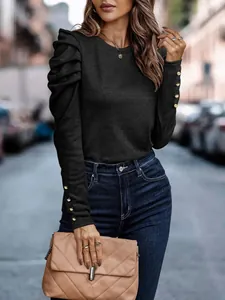 Slim fit black long sleeve top with puff shoulders and gold button cuff details.