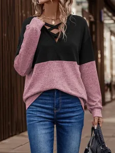 Detail view of V-neck color block sweatshirt with crisscross neckline and drop shoulders.