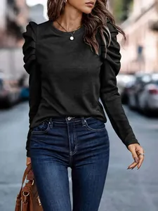 Detail of a chic black long-sleeved top with elegant puff shoulders and a round neckline.