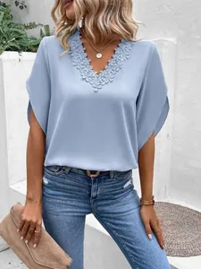 Detail view of women's light blue V-neck blouse with delicate floral lace trim