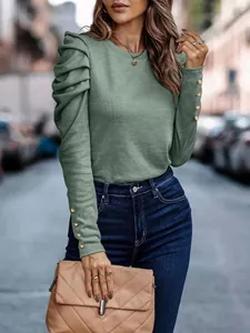 Detail of elegant green knit top with ruched puff sleeves and gold buttoned cuffs.
