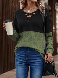 Detail of women's V-neck top with criss-cross straps and green color-block design.