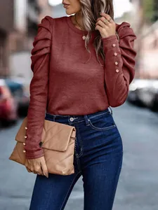 Close-up detail of a burgundy long sleeve puff shoulder top with gold button cuffs