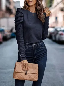 Detail of navy slim fit top featuring puffed shoulders and elegant button cuff accents.