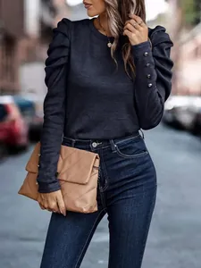 Detail of navy long sleeve top with pleated puff shoulders and gold cuff buttons.