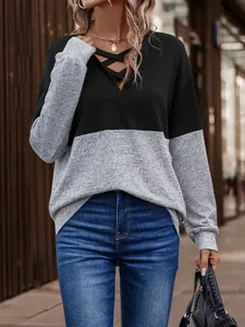 Close-up of women's autumn color-block top with criss-cross V-neck design