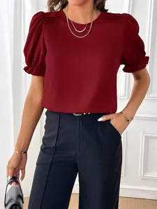 Dettaglio di una camicetta rossa con maniche a sbuffo e un elegante scollo rotondo