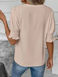 Vista posteriore di una camicetta beige con maniche a sbuffo e polsini elastici a balze