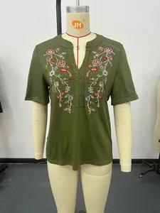 Macro detail of women's olive green top featuring floral embroidery and lace trim V-neck