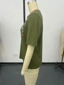 Detailed side view of a dark green women's t-shirt featuring intricate floral embroidery