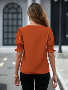 Vista posteriore della camicetta arancione con maniche a sbuffo e polsini a punto smock