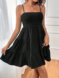Détail du tissu texturé et du corsage froncé sur une robe noire à fines bretelles et volants