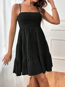 Détail d'une robe noire à bretelles avec bustier smocké et jupe à étages.