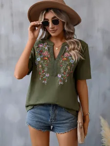 Detailed view of green boho top with intricate floral embroidery and lace V-neck trim