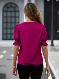 Vista posteriore di un'elegante camicetta magenta con maniche a sbuffo e polsini arricciati