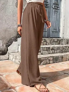 Close-up detail of women's stylish brown wide-leg pants with bubble grid texture