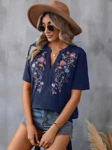 Detailed shot of a navy blue women's top featuring colorful floral embroidery and lace trim