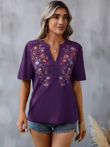 Detailed view of women's purple top with floral embroidery and lace-trimmed V-neck