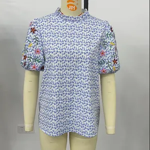 Vue macro de broderies florales colorées sur une blouse blanche à manches courtes froncées